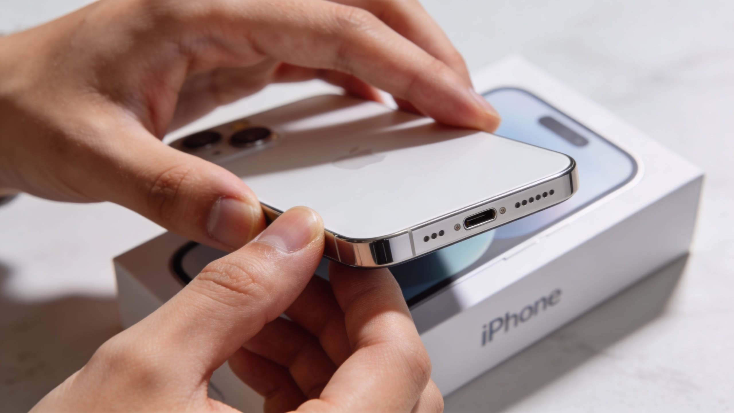 Refurbished iPhone 13 Mini Buyer's Guide (2026) 168 A person holding a silver iPhone above its original white product retail box on a table.
