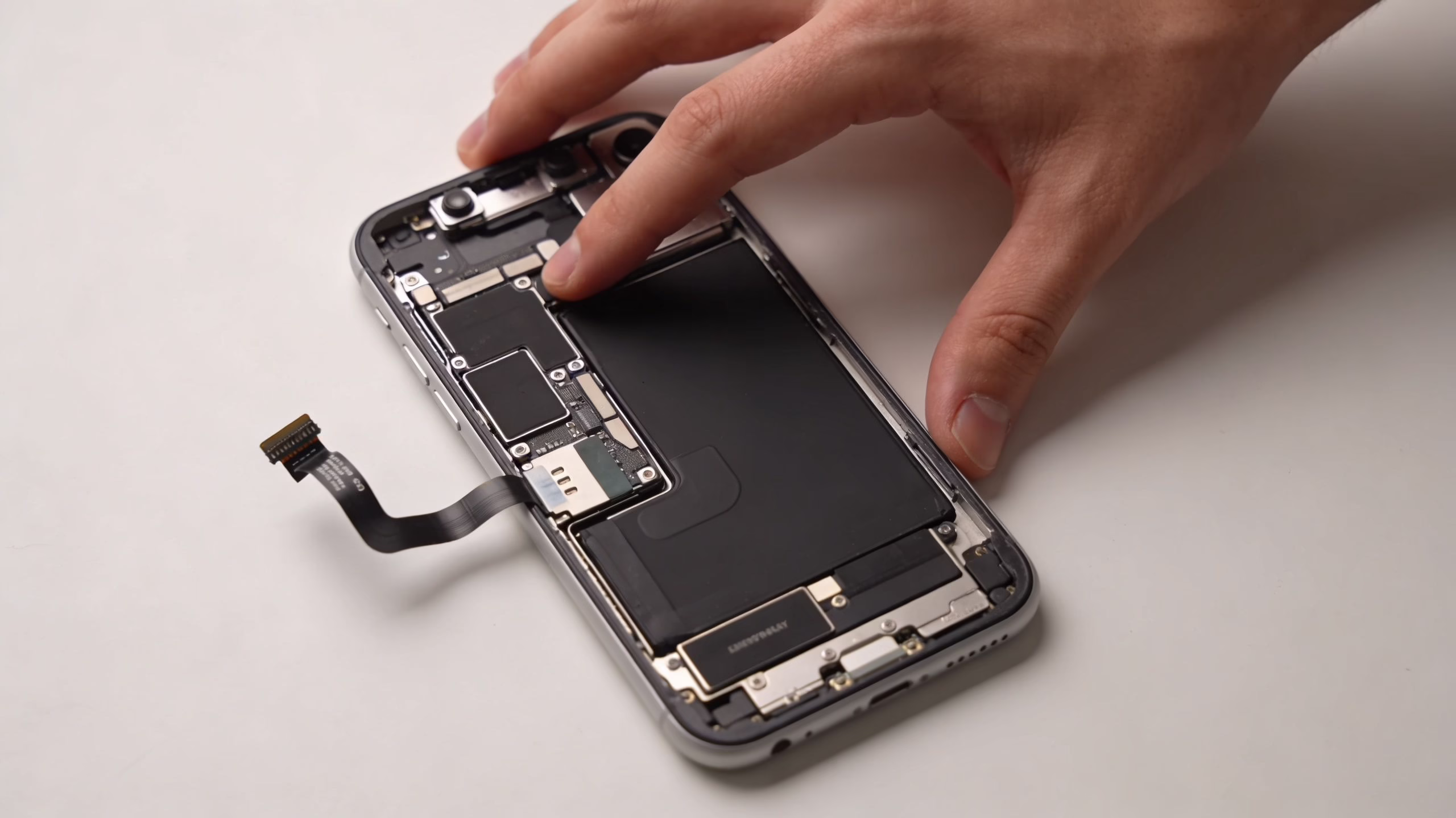 How to Repair Broken iPhone Screen 2 A technician carefully repairs a smartphone, holding the internal components of a disassembled iPhone device.