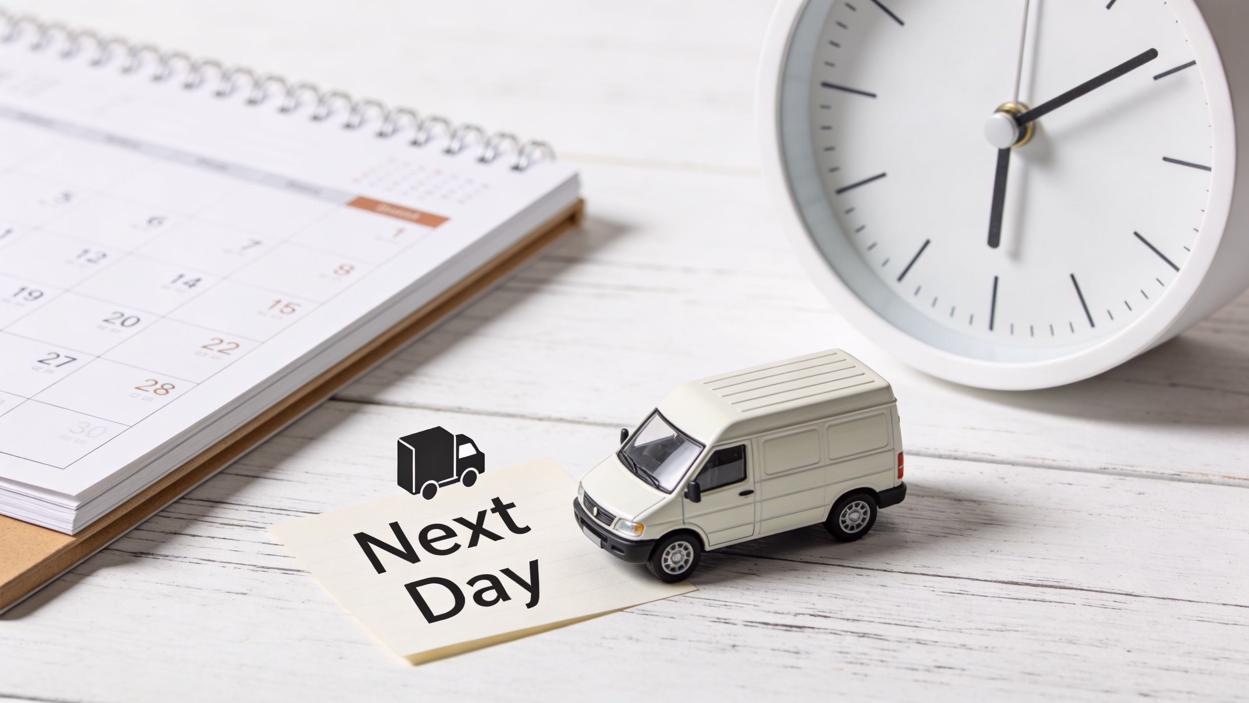 Refurbished iPhone Next Day Delivery UK: 2026 Buying Guide 2 A toy delivery van, a calendar, and a clock on a wooden table, representing next day delivery services.