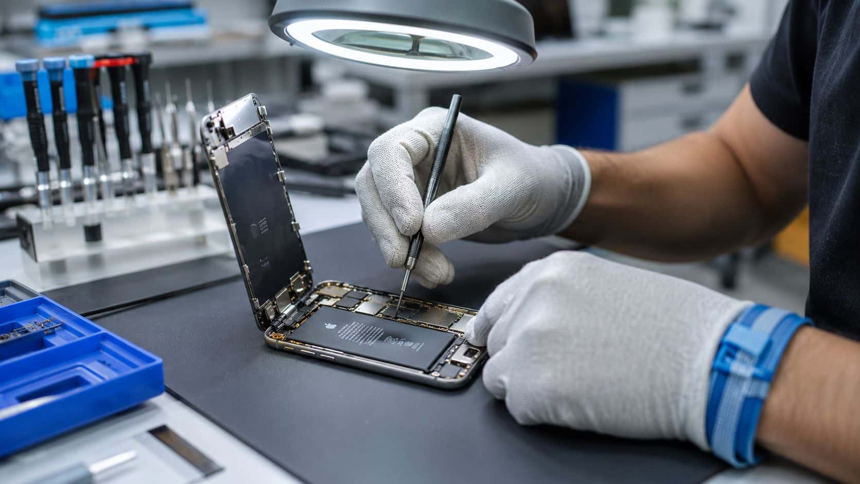 How to Check Refurbished iPhone Quality: A Buyer's Guide 124 A technician wearing white gloves uses a precision screwdriver to repair an open Apple iPhone smartphone.