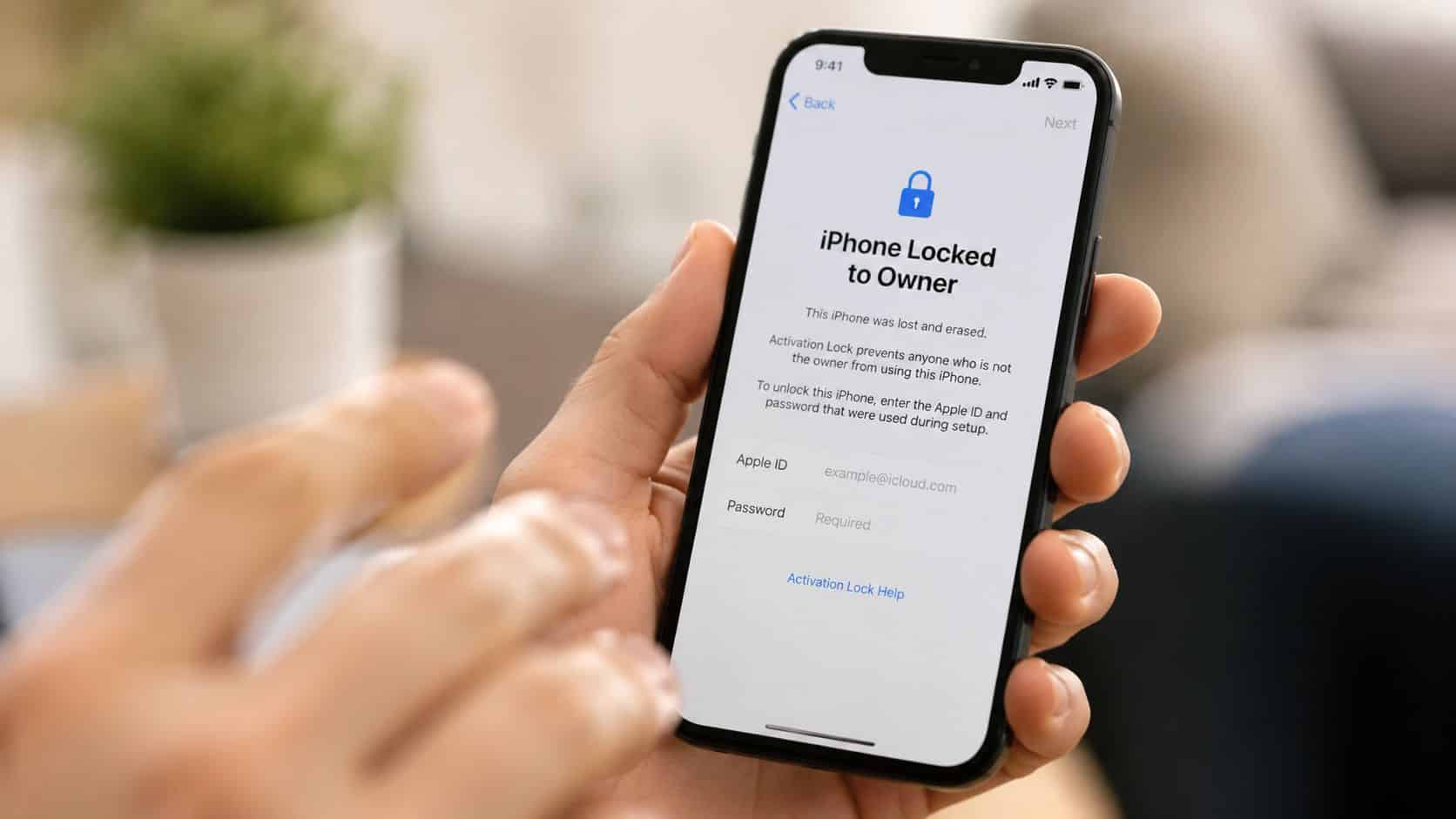 Refurbished iPhone Unlocked UK Meaning Explained by Experts 2 A hand holding an iPhone displaying an Activation Lock screen stating the device is locked to owner.